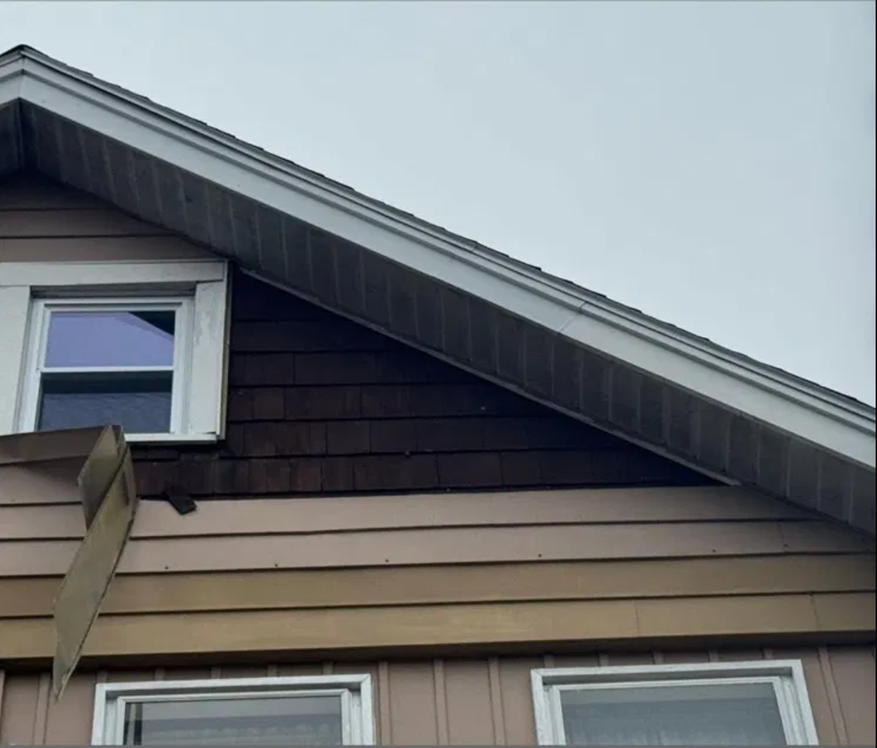 Dark wood shingle gable before Prime Care siding replacement